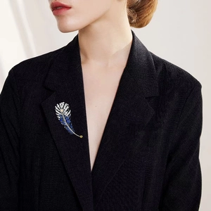 Lussuosa spilla a piuma con zirconi e pietre blu su un elegante blazer nero