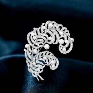 Detailed view of silver feather brooch with shimmering crystals and freshwater pearls