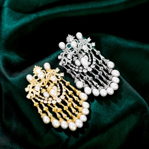 Macro view of gold and silver luxury brooch featuring crystals, pearls and tassels