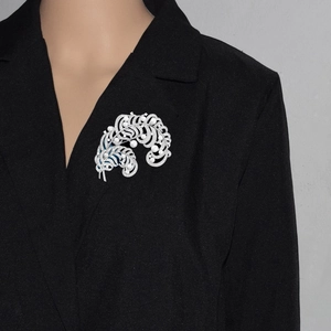 Detail of luxury feather brooch with white pearls and blue enamel on a black blazer