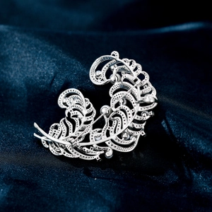 Detailed back view of silver feather brooch with pearl and pin closure on silk
