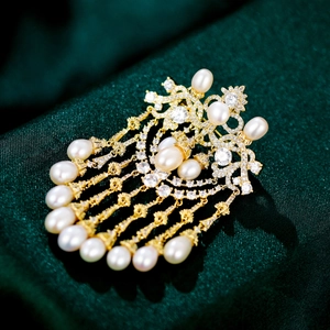 Macro shot of luxury brooch with gold tassel, white pearls, and sparkling zircons