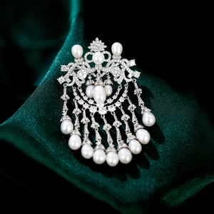 Detailed close-up of a luxury pearl brooch with silver metal tassels and zircon crystals