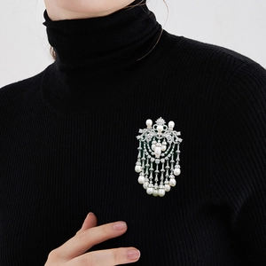 Macro detail of luxury crystal tassel brooch with pearls on a black sweater