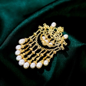 Close-up of vintage gold brooch with teardrop pearls and intricate pavé rhinestone tassel