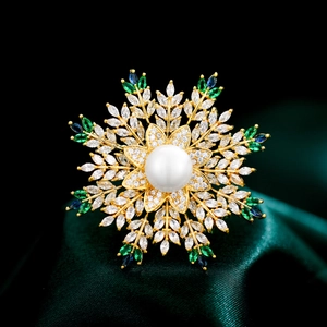 Luxury snowflake brooch with large pearl and colorful gemstones on green velvet base