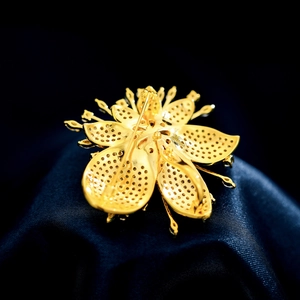 Rückansicht der goldenen Blumenbrosche mit filigraner Wabenstruktur und Metallnadel