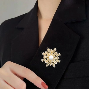 Detailed view of luxury gold snowflake brooch with pearls on black blazer