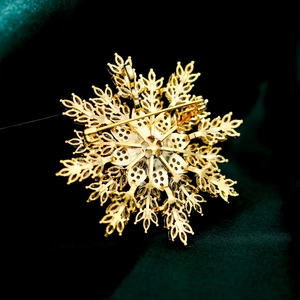 Macro detail of gold snowflake brooch back showing the pin fastener and pendant loop