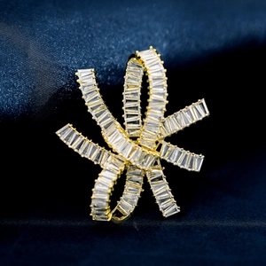 Detail of gold ribbon brooch with baguette-cut zircon inlay on blue silk fabric