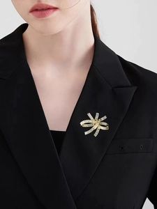 Close-up of a luxury gold bow brooch with baguette zircons on a black blazer