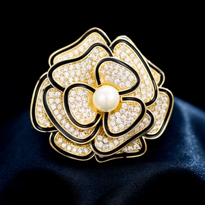 Dettaglio della spilla a camelia con perla centrale e bordi in smalto nero