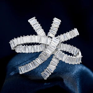Elegant silver-toned bow ring featuring baguette-cut zircon stones on a blue silk background