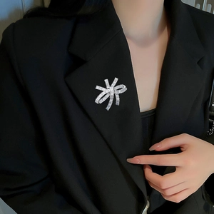 Elegant silver zircon brooch with ribbon design worn on a black blazer lapel