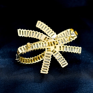 Macro shot showing the secure back pin and hollow metal structure of a gold bow brooch