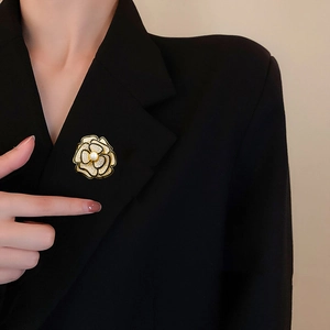 Dettaglio della elegante spilla a camelia con smalto nero e perla su una giacca