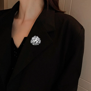Elegante spilla a camelia bianca e nera con perla sul bavero di un blazer nero