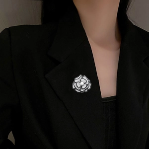 Elegante spilla a camelia con cristalli e perla sul risvolto di un blazer nero