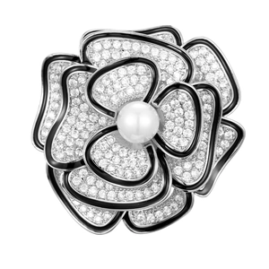 Dettaglio macro della spilla a camelia con perla bianca e petali in smalto nero lucido