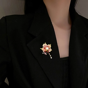 Detail of flower brooch with colorful cubic zirconia and pearl on black blazer