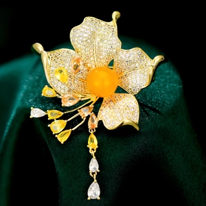 Elegant flower brooch with yellow zircon and tassels on a dark velvet background