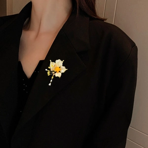 Elegant floral brooch with orange zircon, gold petals and teardrop tassels on black blazer