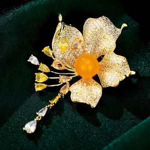 Macro shot of gold flower brooch with colorful zircon petals and teardrop tassels
