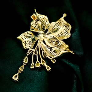 Detail of flower brooch with hollow texture, pin closure and teardrop tassel charm