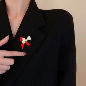 Detail of red enamel bow brooch with micro-pave zircons on a black blazer lapel