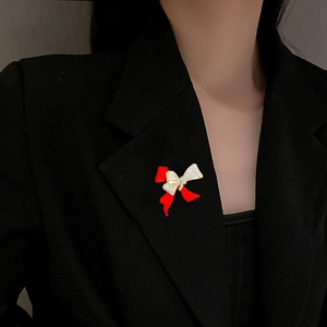 Elegant red bow brooch with sparkling cubic zirconia on black blazer lapel for women