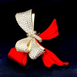 Detailed view of golden bow brooch with micro-pave cubic zirconia on blue satin fabric