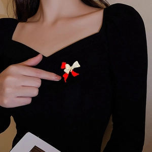 Macro shot of elegant red bow brooch with gold and crystal details on a black garment