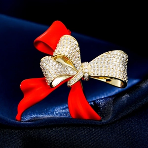 Elegant red enamel bow brooch with sparkling cubic zirconia on dark blue silk background