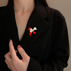 Elegant red enamel bow brooch with sparkling crystals pinned on a black suit lapel