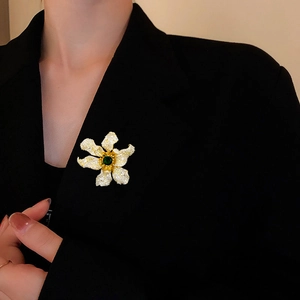 Close-up of sparkling flower brooch with emerald green center on black blazer
