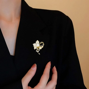Elegant gold flower brooch with white pearl and zircons worn on a black blazer