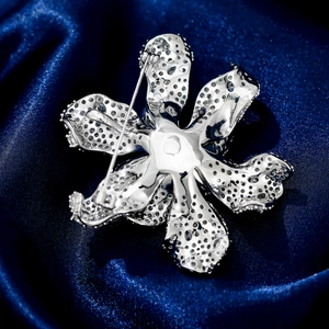 Macro shot of silver flower brooch back showing hollowed-out metal craftsmanship and pin