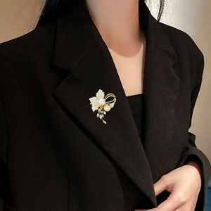 Detail of flower brooch with white pearl and crystal tassels on black blazer