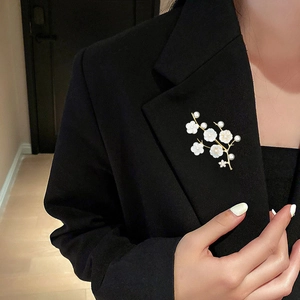 Detail of shell flower brooch with pearls pinned on a elegant black blazer lapel
