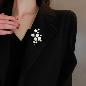 Detailed view of floral shell flower brooch with pearls on a black suit lapel