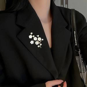 Close-up of shell flower brooch with white pearls on a black suit lapel detail