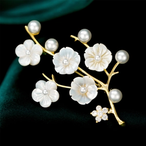 Macro shot of gold floral brooch with shell flowers and pearls on green velvet