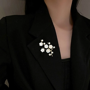 Elegant floral branch brooch with white shell flowers and pearls on a black suit jacket