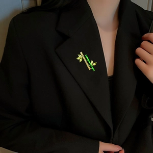 Elegant green bamboo brooch with gold plating and marquise gemstones on black blazer