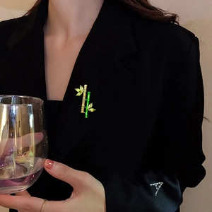 Bamboo brooch with green enamel and crystals on a black suit jacket lapel