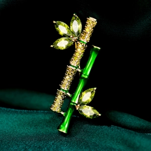 Detailed close-up of bamboo brooch with green enamel and sparkling crystals on silk