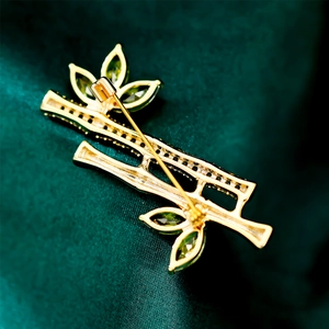 Detailed close-up of bamboo brooch back with pin clasp on green silk fabric