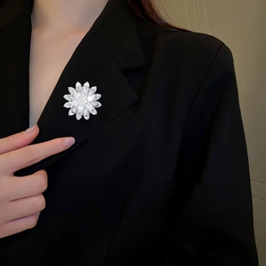 Detailed view of the layered lotus flower brooch featuring sparkling zircons on a black blazer
