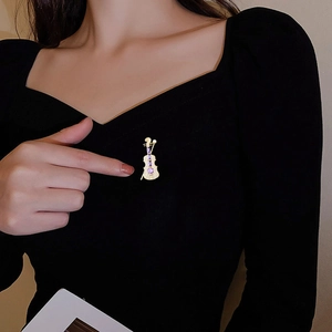 Close-up of violin brooch with gold plating and purple gems on black suit jacket