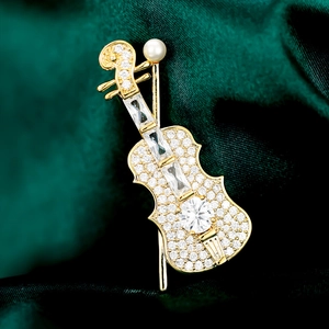 Macro detail of violin brooch with sparkling zircons and pearl on green velvet